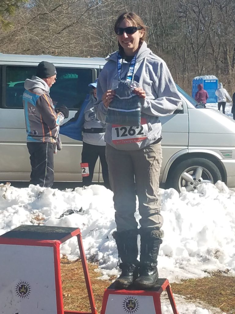 Amie holding up her 3rd place hat at Winter Trail Fest