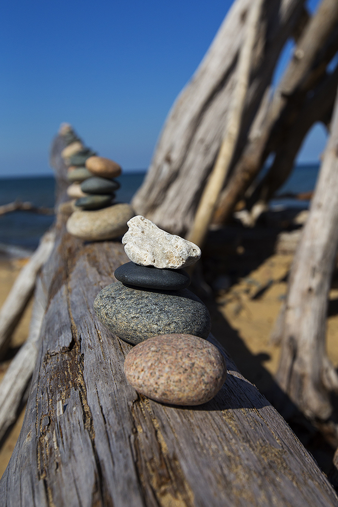 Rocks stacked on drift wood on a beach