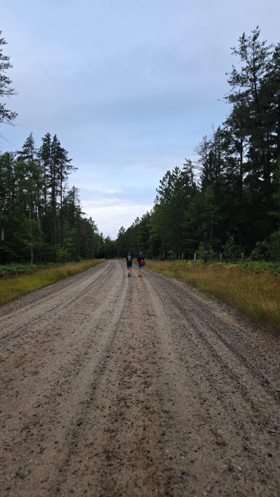 Two people walking on a gravel road to the start line of Tahqua Trail 25K