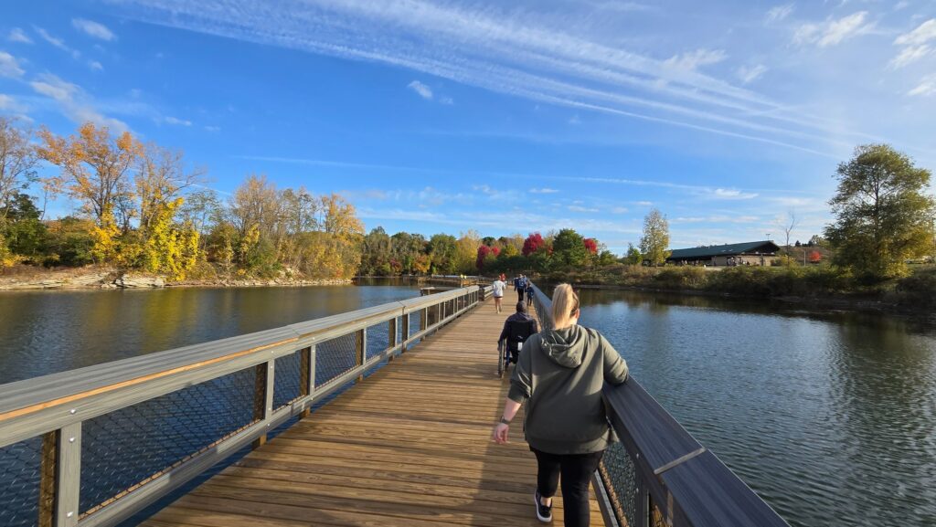 People walking, running, and rolling on the floating boardwalk at Hawk Island Park during the Hot Cider Hustle