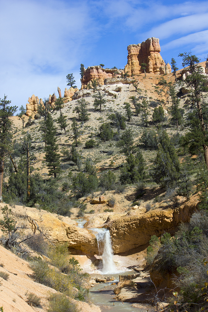 Waterfall falling over a cliff with Hoodoos in the background