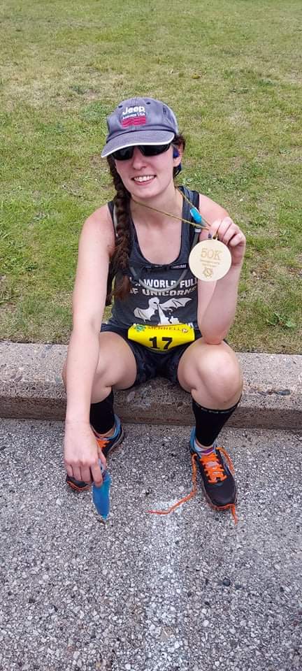 Amie holding up her 50K Medal