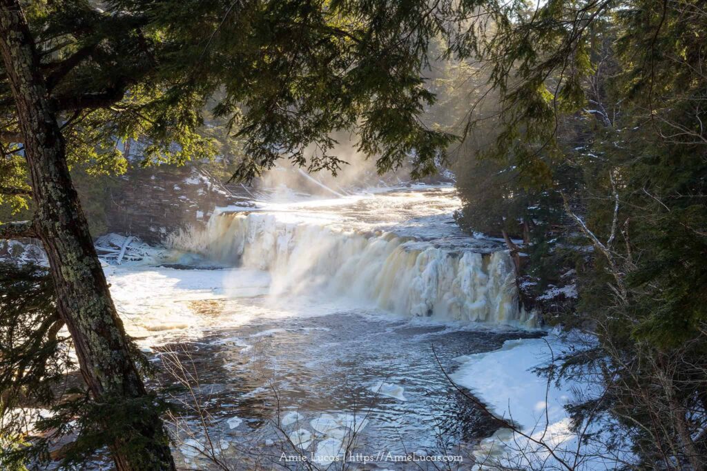 A frozen manabezho Falls framed with evergreens